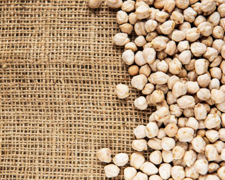 Uncooked dried chickpeas on a old burlap backgroundの写真素材
