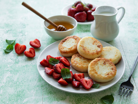 Cottage cheese pancakes, ricotta fritters on ceramic plate with fresh strawberry. Healthy and delicious morning breakfast.の写真素材