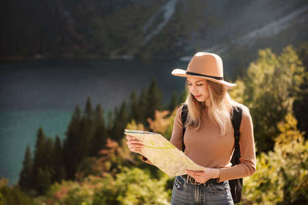 Woman traveler wearing hat and looking at amazing mountains and lake, wanderlust travel concept. Lake Morskoy Eye in the Polish Tatras.の写真素材