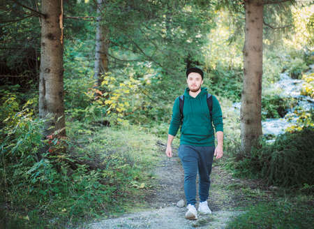 A man with backpack walks in the autumn forest. Hiking alone along autumn forest paths. Travel concept.の写真素材
