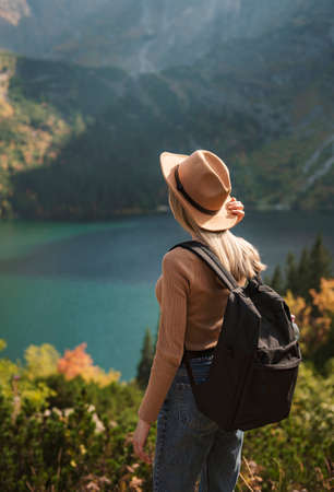 Woman traveler wearing hat and looking at amazing mountains and lake, wanderlust travel concept. Lake Morskoy Eye in the Polish Tatras.の写真素材