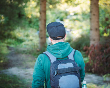 A man with backpack walks in the autumn forest. Hiking alone along autumn forest paths. Travel concept.の写真素材