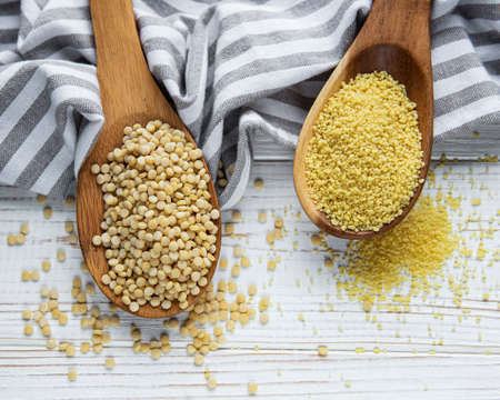Raw Couscous in a wooden spoons on the table