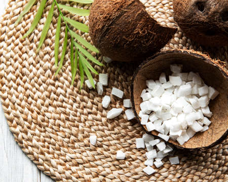 Dried sweet coconut cubes  in bowl on wooden table background.