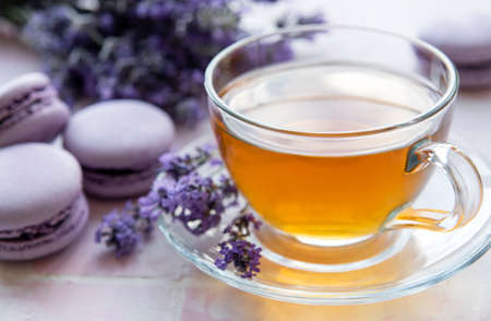 Cup of tea with lavender-flavored macaroon dessert on pink tiles backgroundの写真素材