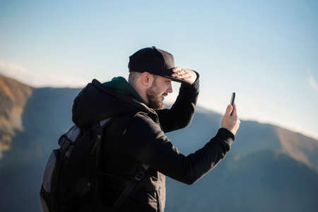 Handsome young man takeson smartphone mountain scenery. Kasprowy Wierch. Poland.の写真素材