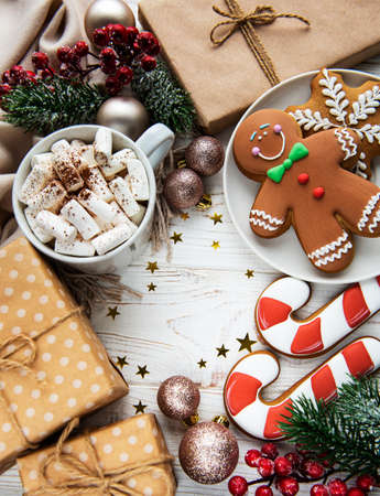 Christmas background with gift box, cocoa and gingerbread cookies. White wooden background.