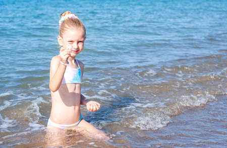 Little girl in a bathing suit playing on the beach by the seaの写真素材