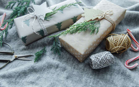 Christmas decorative homemade gift boxes wrapped in brown kraft paper on a gray textile knitted...
