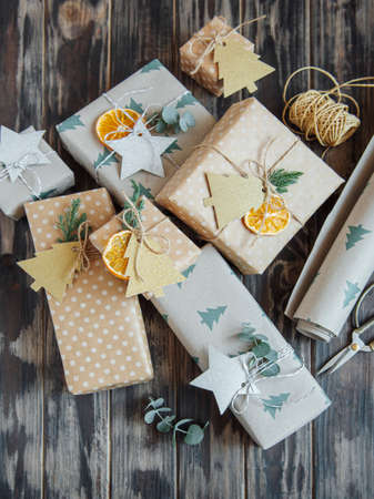 Christmas decorative homemade gift boxes wrapped in brown kraft paper on a dark gray wooden backgroundの写真素材