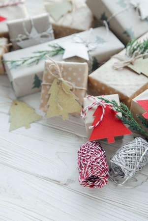 Christmas decorative homemade gift boxes wrapped in brown kraft paper on a white wooden tableの写真素材