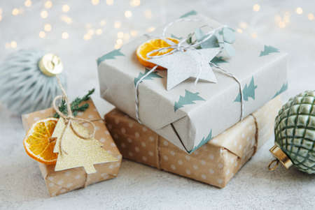 Christmas decorative homemade gift boxes wrapped in brown kraft paper on a gray concrete background