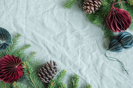 Spruce twigs and paper Christmas decorations on the green linen crumpled textile background