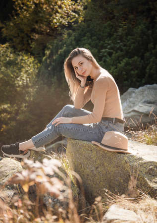 Young woman tourist sitting on the mountain peak and beautiful mountains. Landscape with sporty girl, green forest, hills, sky, lake. Travel and tourism.の写真素材