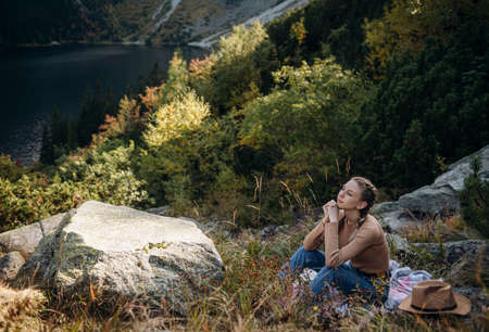 Young woman tourist sitting on the mountain peak and beautiful mountains. Landscape with sporty...
