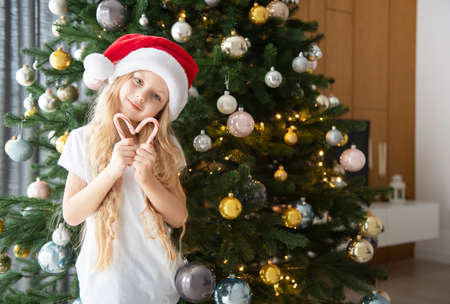 A girl with gifts plays near the Christmas tree. Living room interior with Christmas tree and...