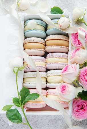 Box with delicious colorful macaroons and rose flowersの写真素材
