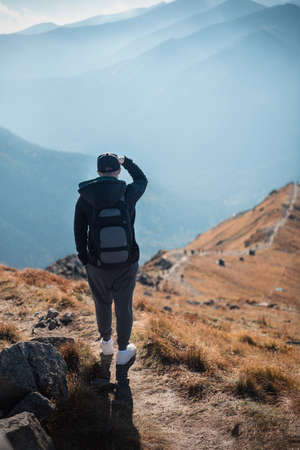 Handsome young man looking away in front of mountain on sunny day. Kasprowy Wierch. Poland.の写真素材