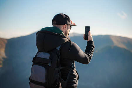 Handsome young man takeson smartphone mountain scenery. Kasprowy Wierch. Poland.
