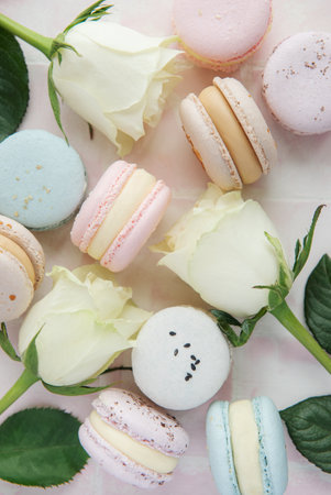 Beautiful colorful tasty macaroons and pink roses on a pink tile backgroundの写真素材