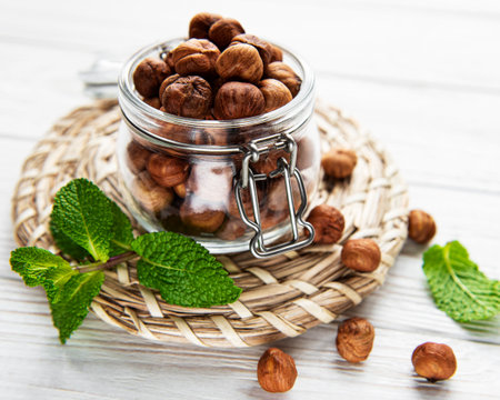 Peeled hazelnuts in a glass jar on white wooden backgroundの写真素材