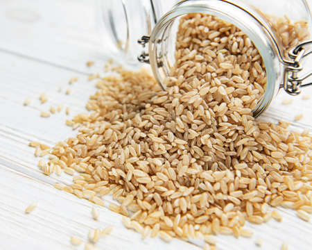 Raw brown rice on white wooden backgroundの写真素材