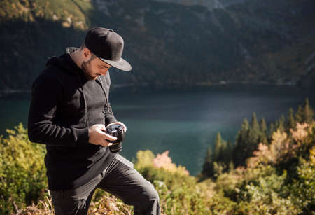 Young man photographer taking photographs with digital camera in a mountains. Travel and active lifestyle conceptの写真素材