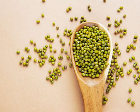 Raw mung beans in the wooden spoon on a brown backgroundの写真素材
