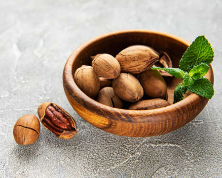 Pecan nuts in bowl on a gray concrete background
