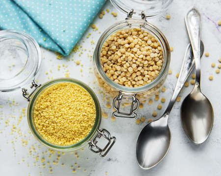 Raw Couscous in a glass jars and spoons on the tableの写真素材