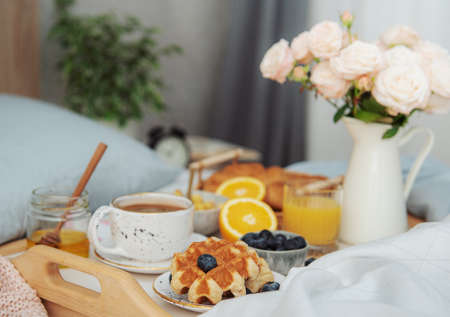 Romantic breakfast with coffee, waffles, orange juice and rose flowers.の写真素材