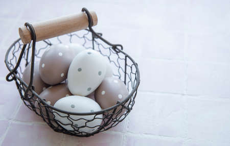 A basket with Easter eggs on pink tile backgroundの写真素材