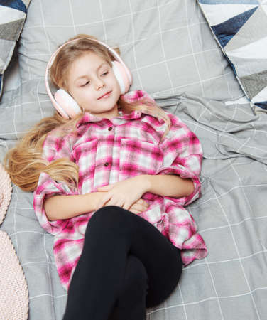 Adorable little girl in headphones enjoy with a music.の写真素材