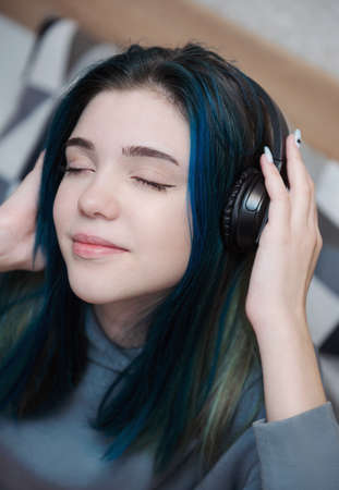 Young teenager girl with blue hair and headphonesの写真素材