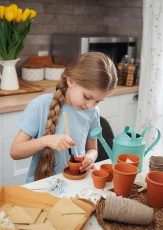Little girl sitting at the table at home, sowing seeds into flower pots. home gardeningの写真素材