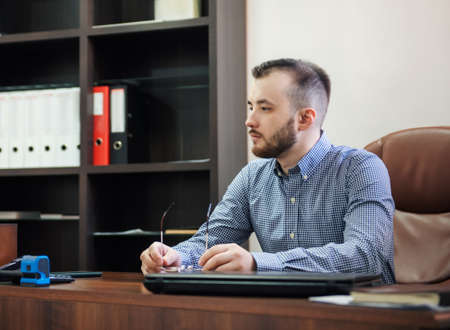 Young Businessman in shirt working on his laptop in an officeの写真素材