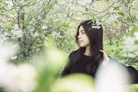 Pretty teen girl are posing in garden near blossom apple tree with pink flowers. spring time