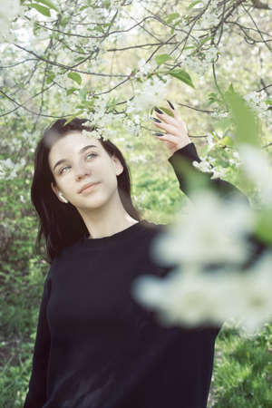 Pretty teen girl are posing in garden near blossom apple tree with pink flowers. spring timeの写真素材