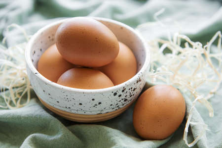 Bowl of fresh  brown eggs on concrete background
