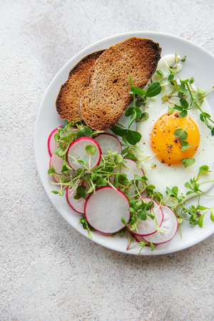 Delicious gourmet Breakfast. Rye bread  with fried egg,  freshly ground pepper and salad with redish...