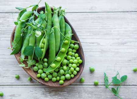 Bowl with young fresh juicy pods of green peas on a wooden background. Healthy organic food.の写真素材