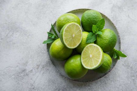 Green  Limes with fresh mint leaves on  plate, concrete backgroundの写真素材