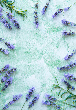 Lavender flowers and leaves creative frame on a green wooden background. Top view, flat lay. Floral...