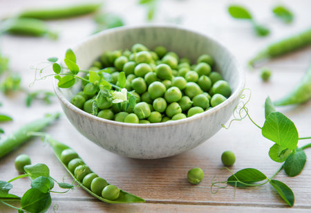 Bowl with young fresh juicy pods of green peas on a wooden background. Healthy organic food.の写真素材