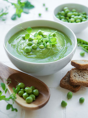 Fresh green pea soup bowl on white tile backgroundの写真素材
