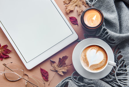 Home workplace. Cup of coffee and tablet, leaves and warm blanket.  Autumn, fall concept. Flat lay, top view.の写真素材
