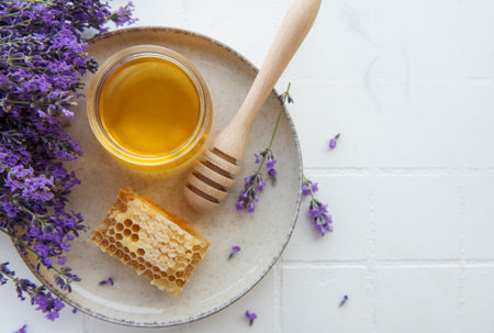 Glass of honey, honeycomb and lavender flowersの写真素材