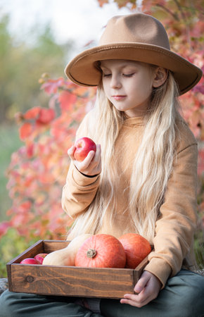 Little girls sitting among hay bales and pumpkins in the autumn gardenの写真素材