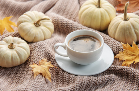 White pumpkins, coffee and autumn leaves on a grey knitted sweater. Autumn home decor.の写真素材