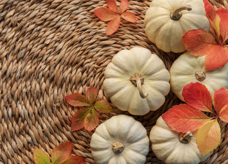 Thanksgiving season still life with small pumpkins and fall leaves over wicker mat  backgroundの写真素材
